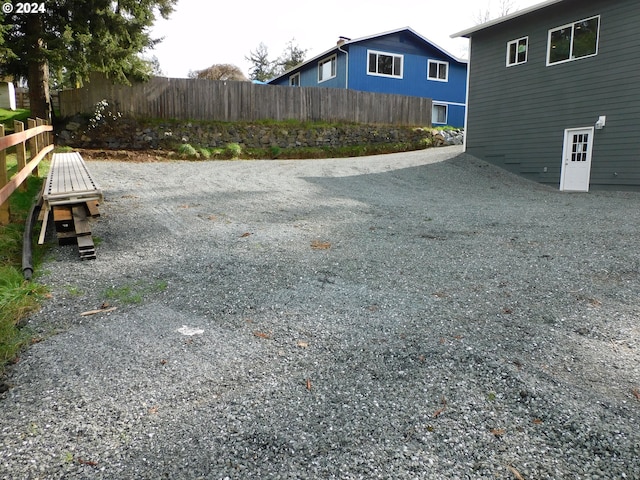 view of yard with gravel driveway and fence