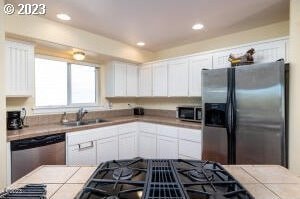 kitchen featuring sink, appliances with stainless steel finishes, tile countertops, and white cabinetry