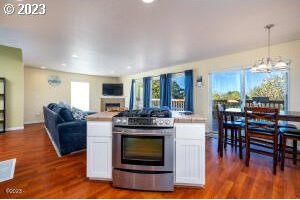 kitchen featuring stainless steel range with gas stovetop, hanging light fixtures, a notable chandelier, plenty of natural light, and white cabinets