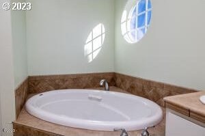 bathroom with a relaxing tiled tub and vanity