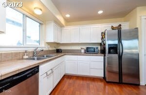 kitchen with sink, appliances with stainless steel finishes, dark hardwood / wood-style floors, and white cabinetry