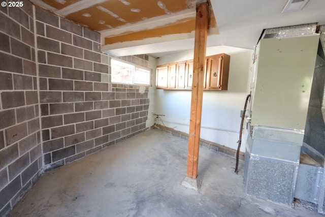 basement featuring concrete block wall, heating unit, and visible vents