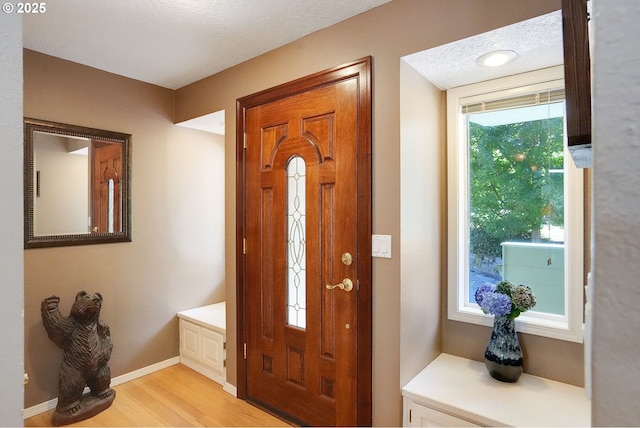 entrance foyer featuring light wood-style floors, a textured ceiling, and baseboards