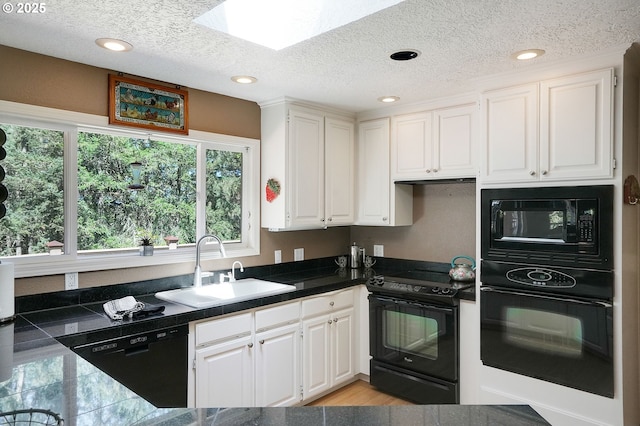 kitchen featuring a textured ceiling, a sink, white cabinets, tile counters, and black appliances