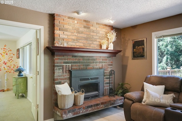 living area featuring a brick fireplace, baseboards, and a textured ceiling