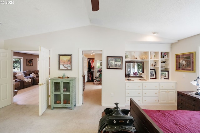 bedroom featuring lofted ceiling, a textured ceiling, light colored carpet, a ceiling fan, and a spacious closet