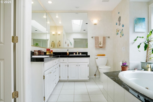 full bathroom with a skylight, toilet, vanity, tile patterned flooring, and a tub with jets