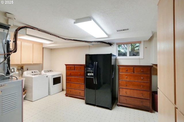 washroom with a textured ceiling, separate washer and dryer, visible vents, cabinet space, and light floors