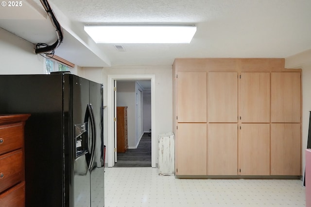 kitchen with light floors, visible vents, black refrigerator with ice dispenser, light brown cabinetry, and a textured ceiling