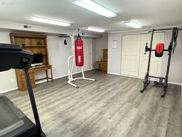 exercise area featuring visible vents, baseboards, and wood finished floors