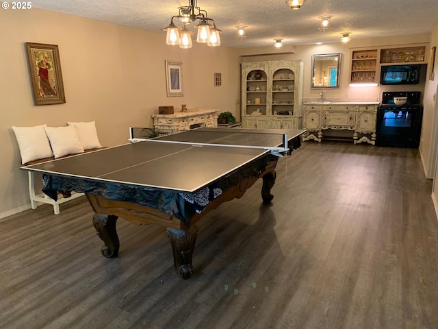 recreation room with a textured ceiling, dark wood-style flooring, and baseboards