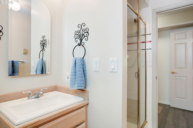 bathroom with wood finished floors, a shower stall, and vanity