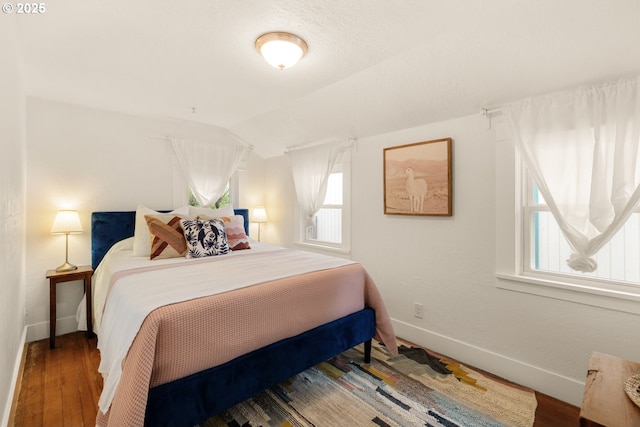 bedroom featuring baseboards, vaulted ceiling, and wood finished floors