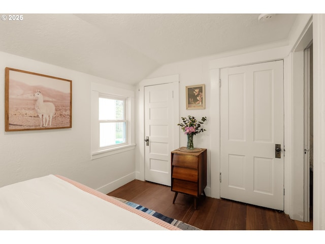 bedroom with baseboards, dark wood finished floors, and lofted ceiling