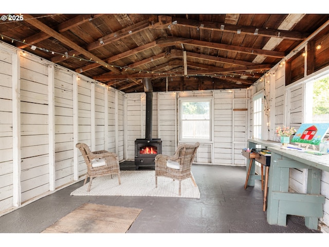 sitting room with a wood stove and vaulted ceiling