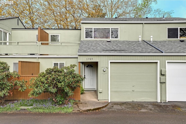 townhome / multi-family property featuring driveway, a shingled roof, a garage, and a balcony