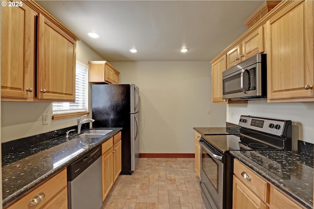 kitchen with baseboards, recessed lighting, dark stone counters, appliances with stainless steel finishes, and a sink