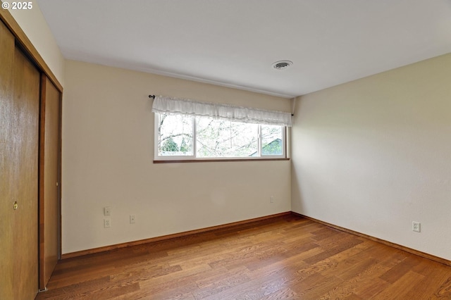 unfurnished bedroom with a closet, visible vents, light wood-type flooring, and baseboards