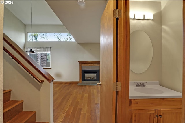 bathroom with a tile fireplace, vanity, and wood finished floors