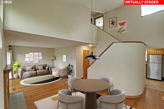 dining area featuring a wealth of natural light, wood finished floors, and a towering ceiling