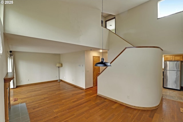 stairway featuring a high ceiling, baseboards, and wood finished floors