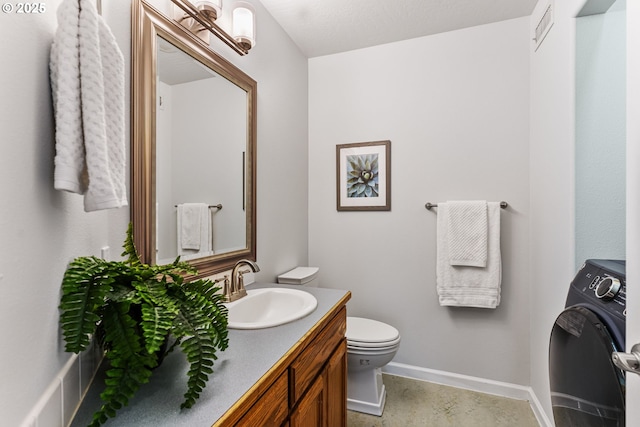 bathroom with vanity, washer / dryer, and toilet