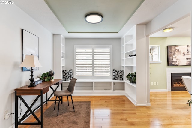 home office featuring a tile fireplace and light hardwood / wood-style flooring