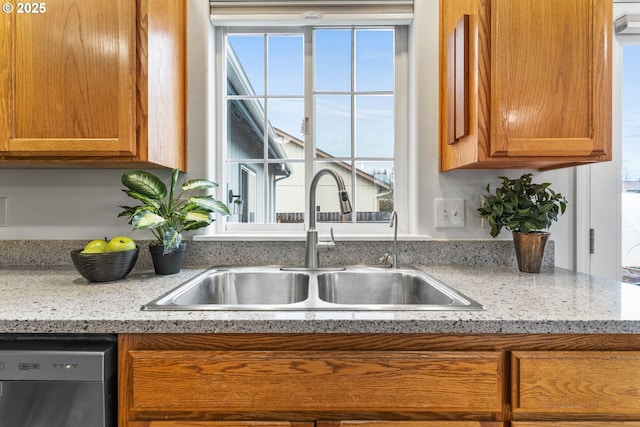 kitchen with a healthy amount of sunlight, black dishwasher, sink, and light stone countertops