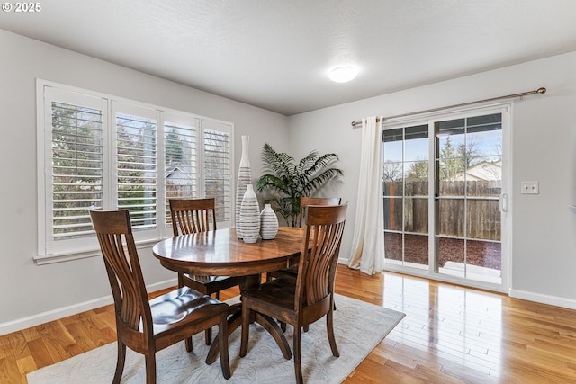 dining area featuring light hardwood / wood-style flooring, a textured ceiling, and plenty of natural light