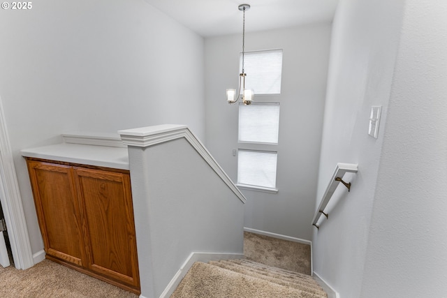 stairs featuring carpet floors, a wealth of natural light, and a notable chandelier