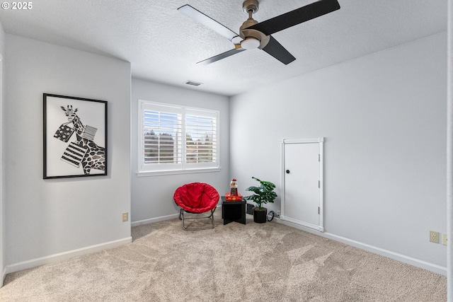 living area with ceiling fan, light colored carpet, and a textured ceiling