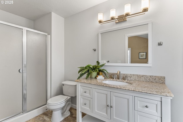 bathroom featuring vanity, a shower with door, and toilet