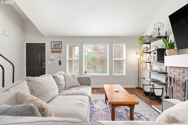 16190 SW Theresa Ct, Beaverton, OR 97007 - living room featuring vaulted ceiling, a textured ceiling, wood finished floors, baseboards, and a brick fireplace