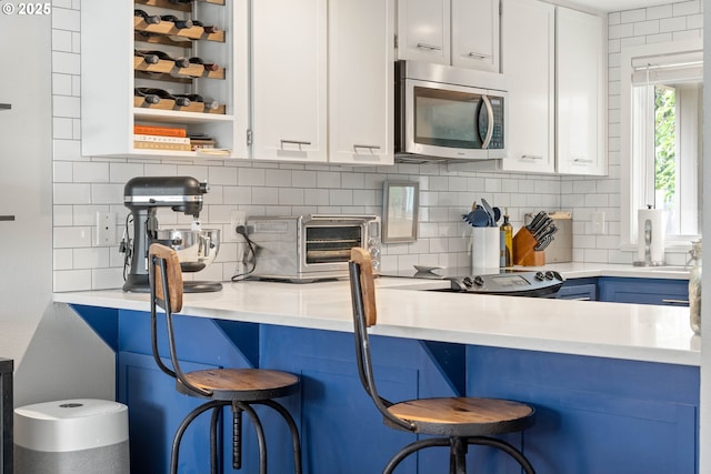 16190 SW Theresa Ct, Beaverton, OR 97007 - kitchen with stainless steel microwave, decorative backsplash, a breakfast bar area, and light countertops