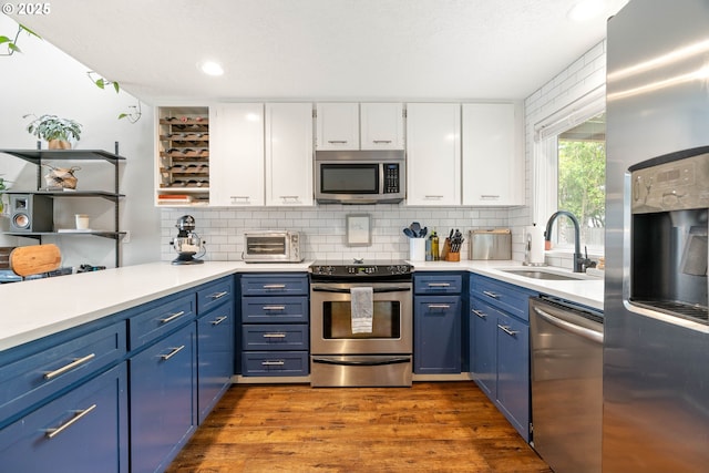 16190 SW Theresa Ct, Beaverton, OR 97007 - kitchen with appliances with stainless steel finishes, a sink, blue cabinetry, white cabinetry, and dark wood-style flooring