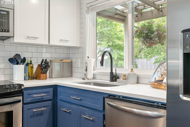 16190 SW Theresa Ct, Beaverton, OR 97007 - kitchen featuring stainless steel appliances, blue cabinetry, a sink, white cabinetry, and tasteful backsplash