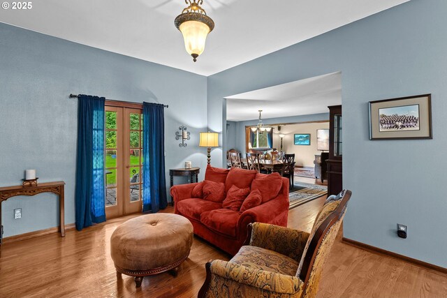 living area with wood finished floors, plenty of natural light, a chandelier, and baseboards