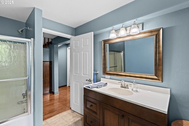 bathroom featuring combined bath / shower with glass door and vanity
