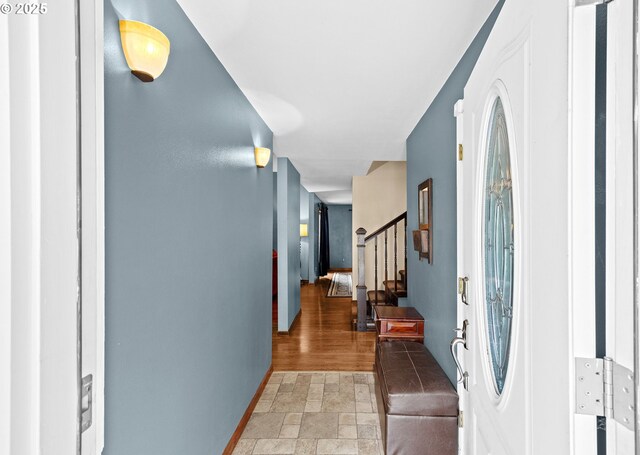 entryway featuring stone finish floors, stairway, and baseboards
