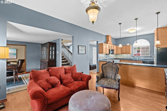 living room featuring light wood-type flooring and stairs