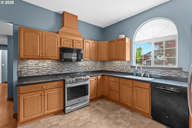 kitchen with black appliances, a sink, dark countertops, tasteful backsplash, and stone finish floors