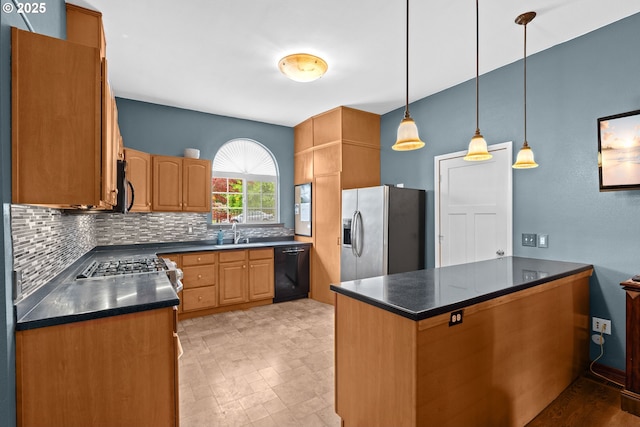kitchen featuring appliances with stainless steel finishes, dark countertops, decorative backsplash, and a sink