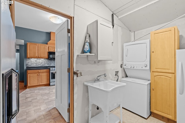 clothes washing area featuring stacked washer / dryer and cabinet space