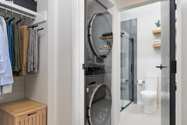 laundry room with stacked washer and clothes dryer and tile patterned flooring