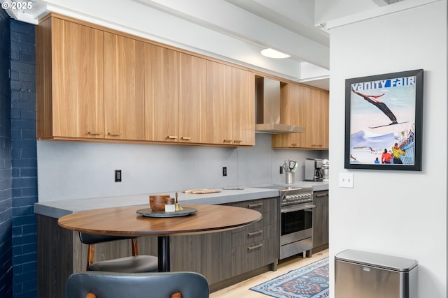 kitchen featuring electric range, a kitchen bar, and wall chimney exhaust hood