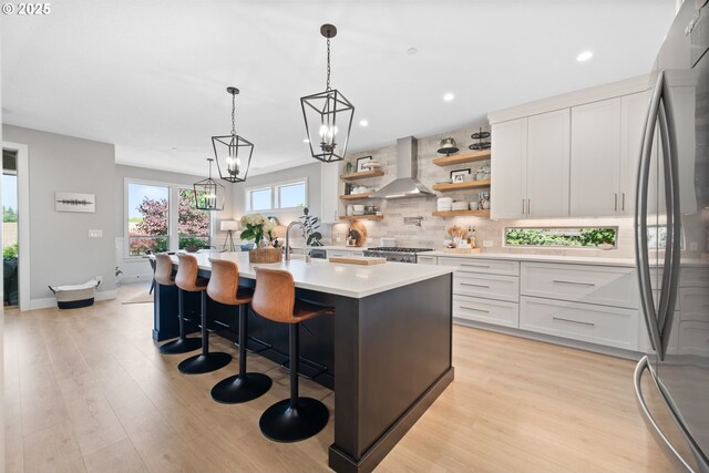 4148 S 11th Cir, Ridgefield, WA 98642 - kitchen featuring freestanding refrigerator, wall chimney range hood, backsplash, white cabinetry, and light countertops