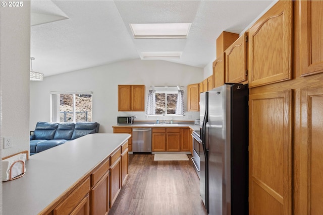 2614 Montana St, North Bend, OR 97459 - kitchen with appliances with stainless steel finishes, wood finished floors, light countertops, vaulted ceiling, and a sink