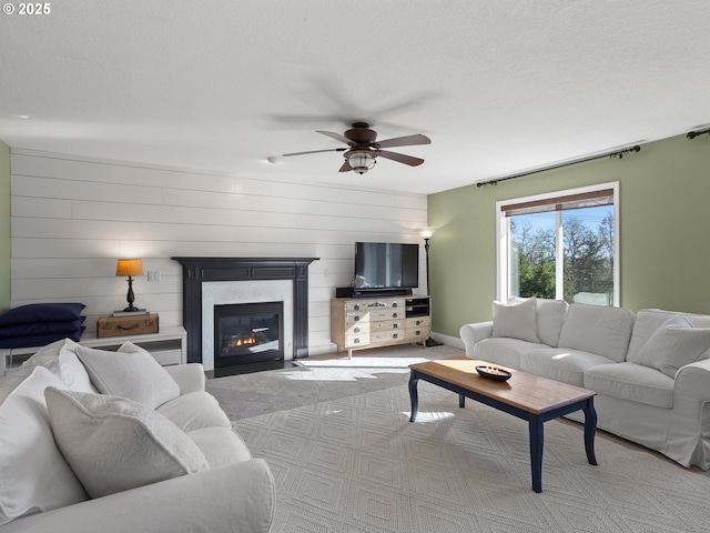 living area featuring a textured ceiling, carpet floors, a high end fireplace, and a ceiling fan