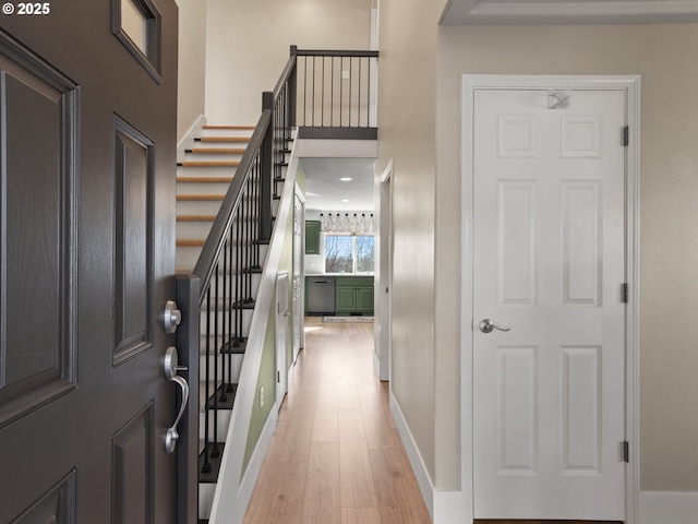 foyer featuring stairway, light wood-type flooring, a towering ceiling, and baseboards