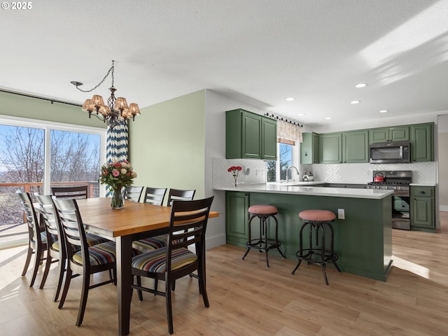 dining area featuring light wood finished floors, a notable chandelier, and recessed lighting